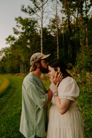 An intimate photoshoot in a lush green field with trees in the background.