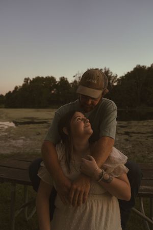 A romantic sunset moment shared on a wooden deck with nature in the background.