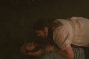 An intimate portrait of a couple laying together in a darkened outdoor setting.