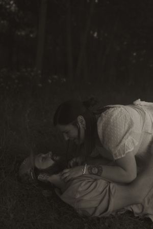 A romantic black and white photo shows a couple in a close embrace on the ground.