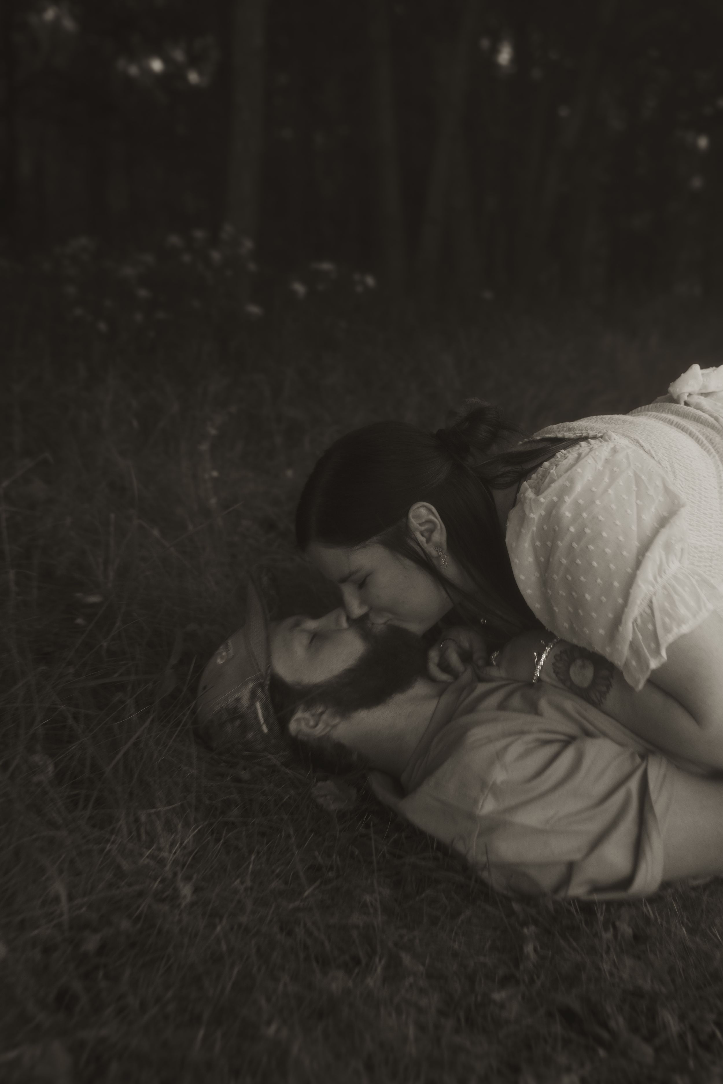 A romantic black and white photo of a couple lying in grass.