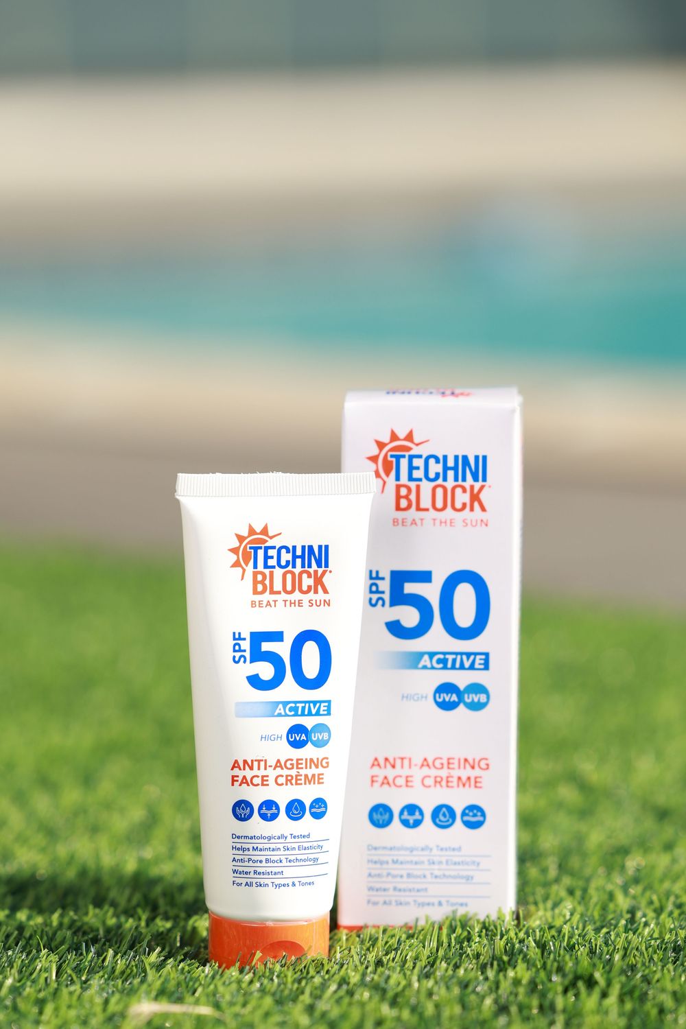 Techniblock SPF 50 Active Anti-Ageing Face Creme tube and box displayed on green grass near a pool.