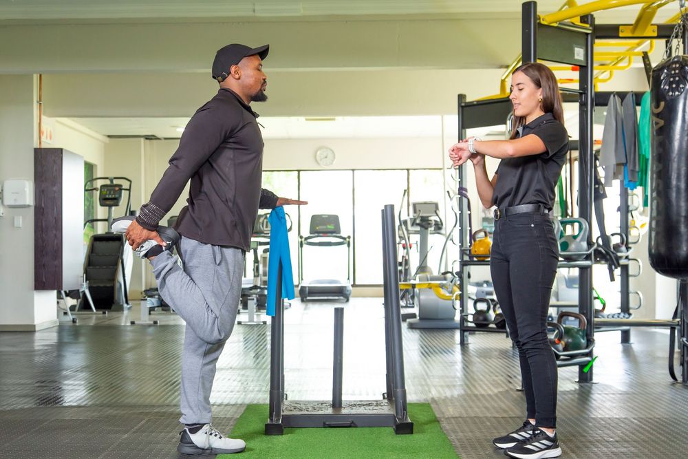 Two people having a conversation while standing in a modern fitness facility with exercise equipment.