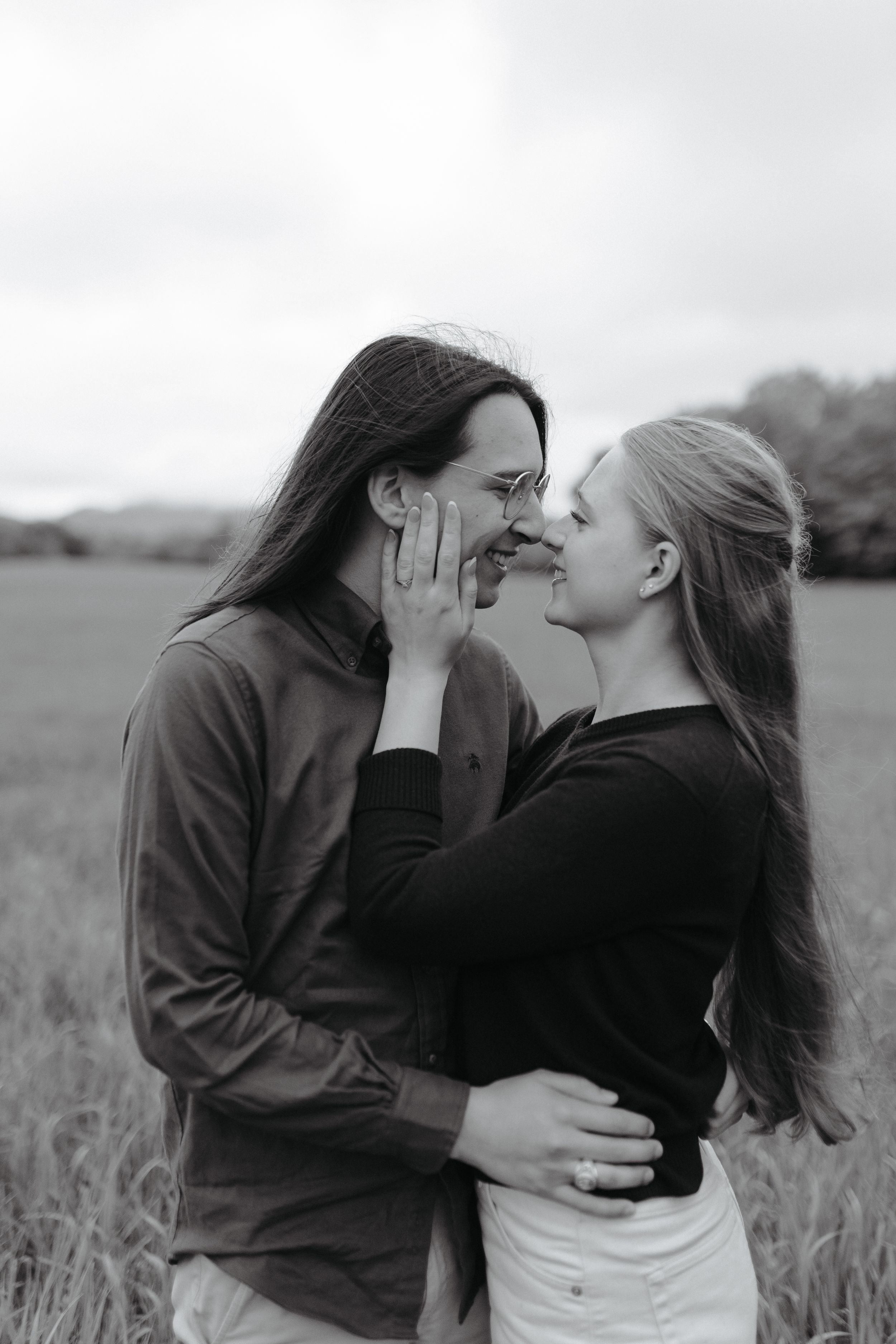 A romantic black and white photo of a couple sharing an intimate moment in a field.