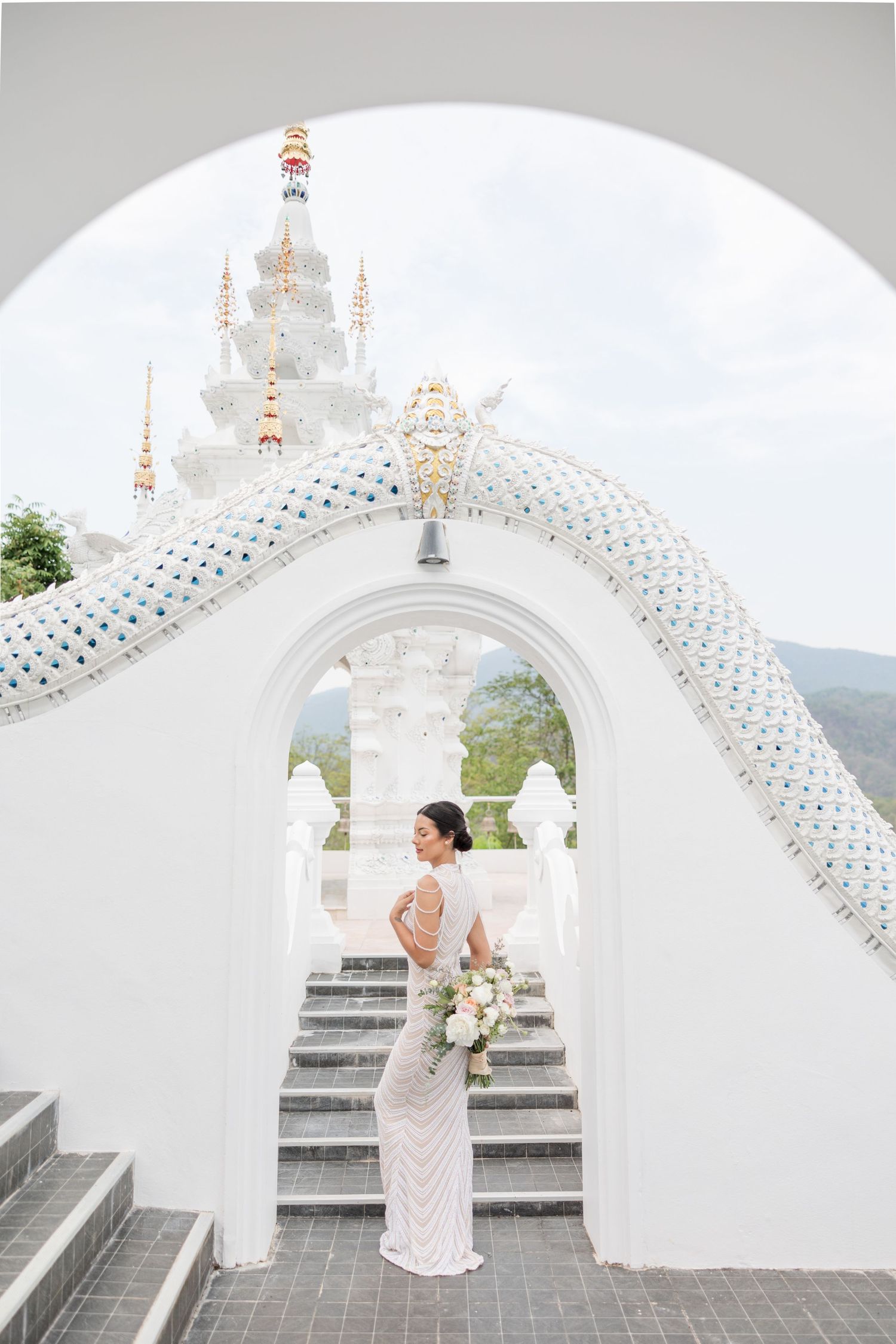 A stunning white temple with ornate details and curved archway creates an elegant architectural setting.
