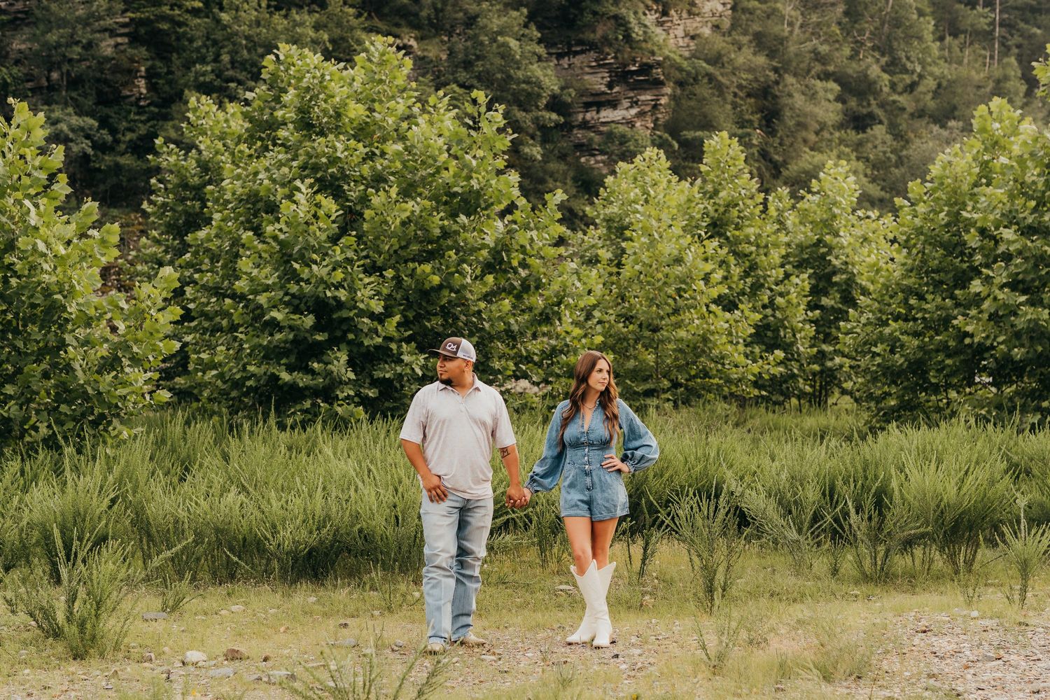 Two people walk together on a grassy trail surrounded by lush green trees on a sunny summer day in Broken Bow, Ok..