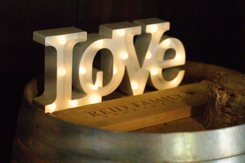 Illuminated white LOVE marquee letters glowing on a wooden surface in warm lighting.
