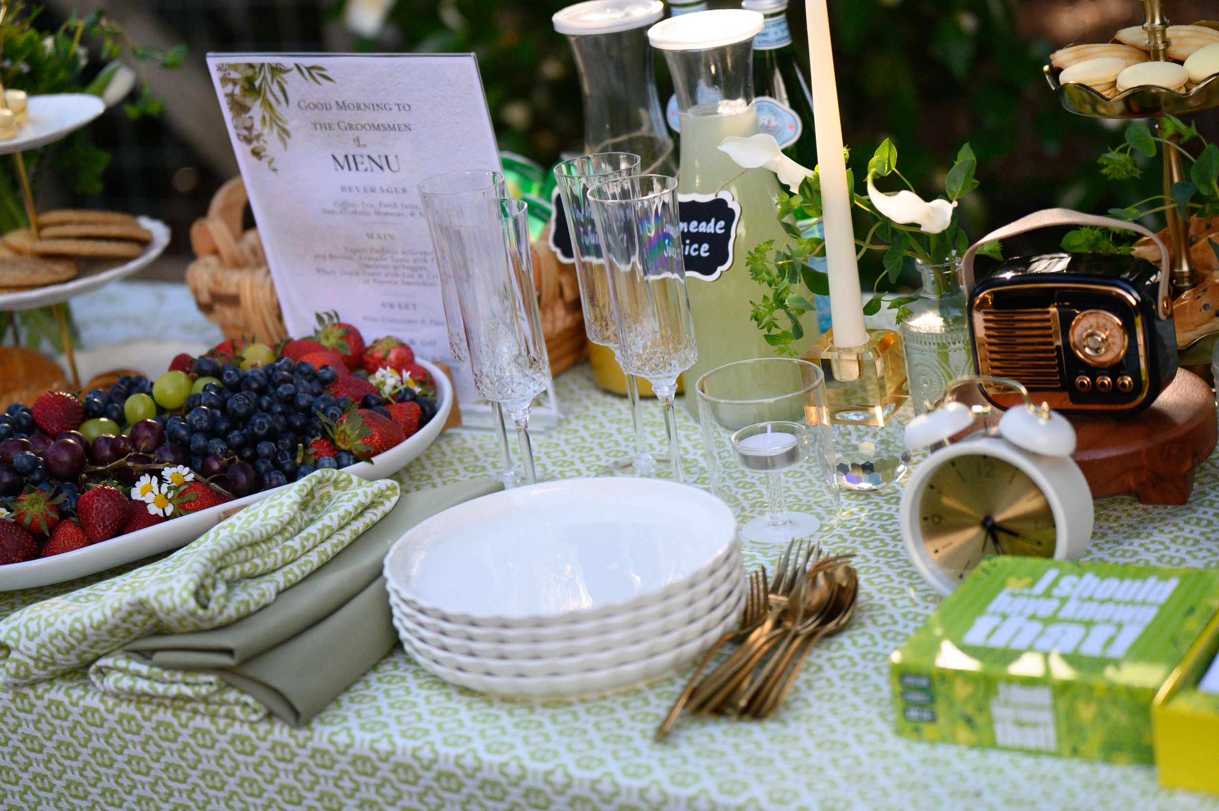 Table setting with white plates, glassware, fresh berries and vintage decorations at an outdoor party.