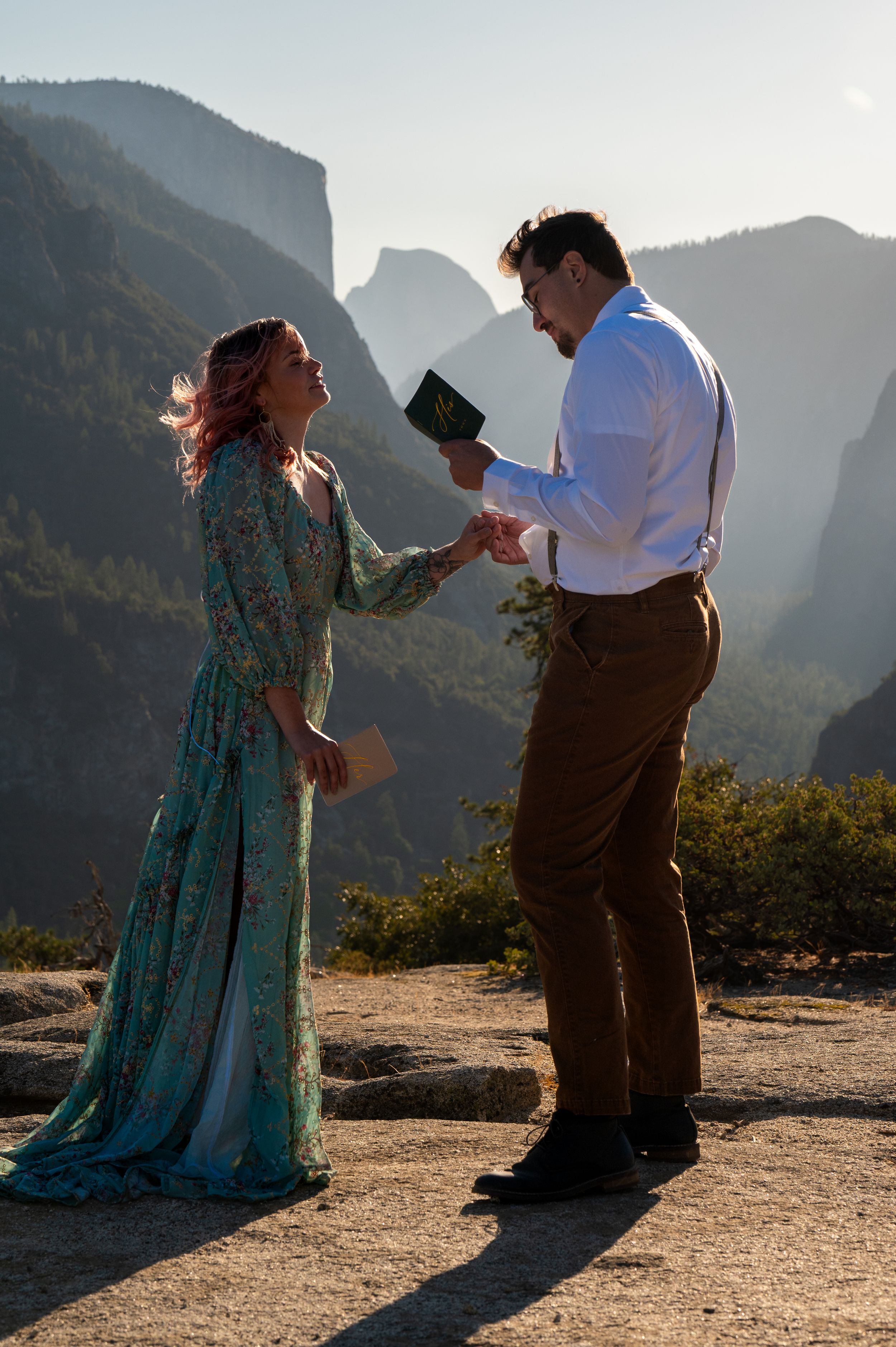 A couple shares a tender moment during a wedding ceremony with Half Dome visible in the background at Yosemite.