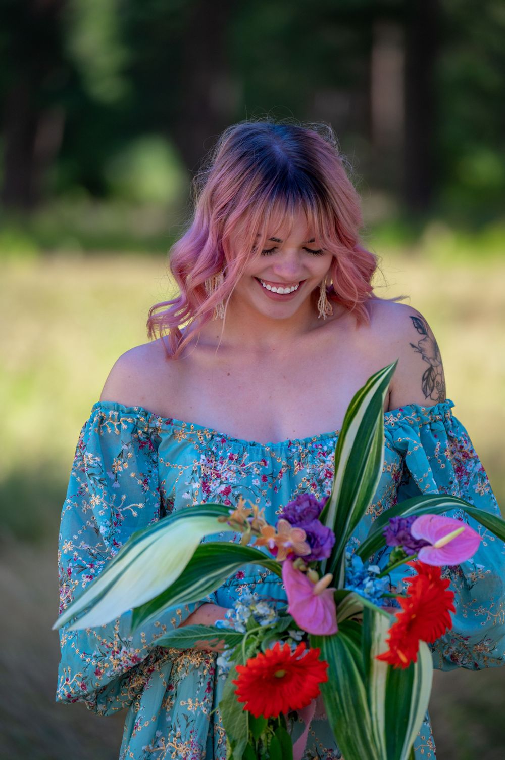 A joyful person in a blue floral dress holds a colorful bouquet of flowers in a sunny meadow.