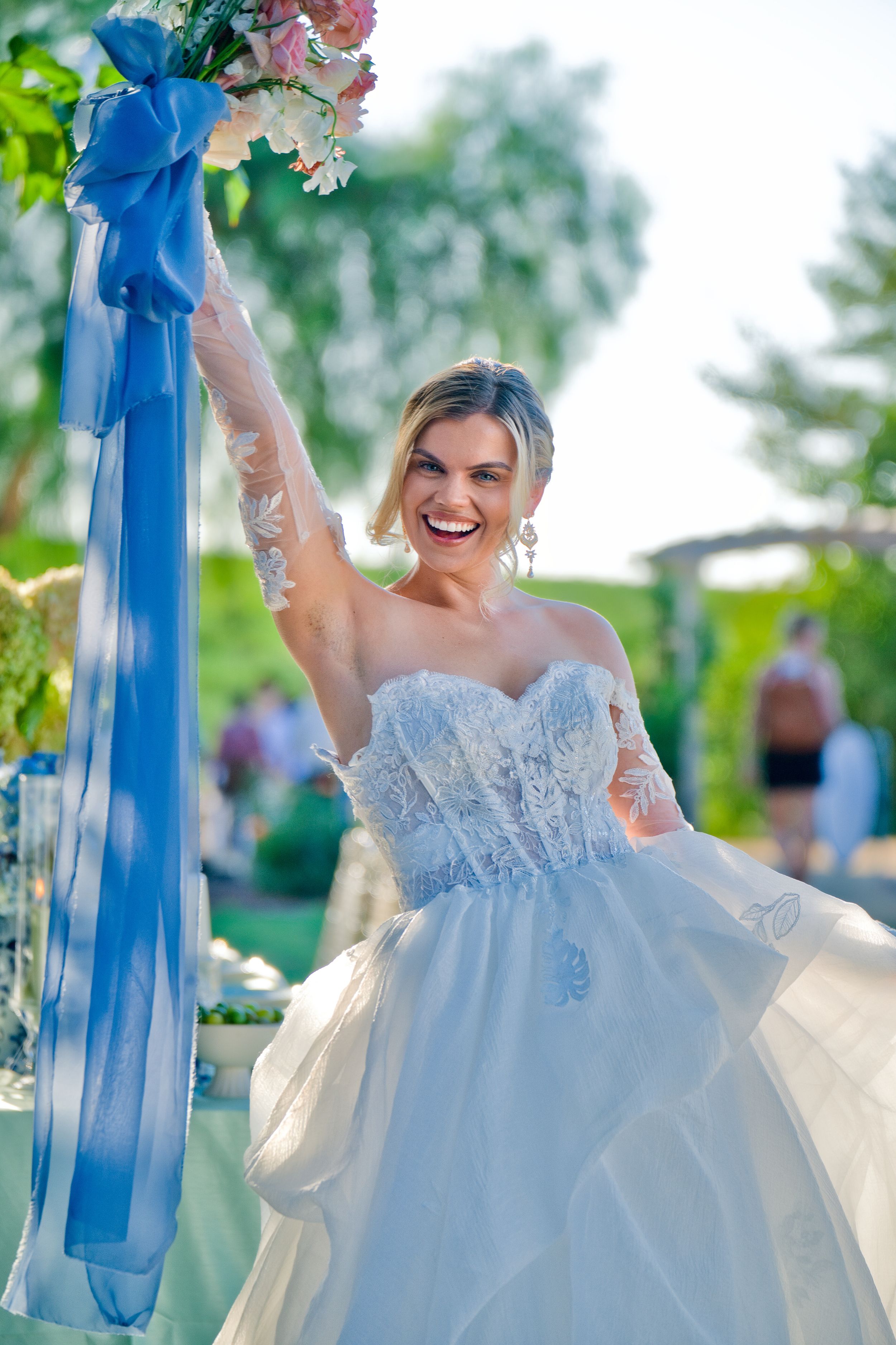 Beautiful wedding decor featuring a white floral arch with flowing blue ribbons in an outdoor garden setting.