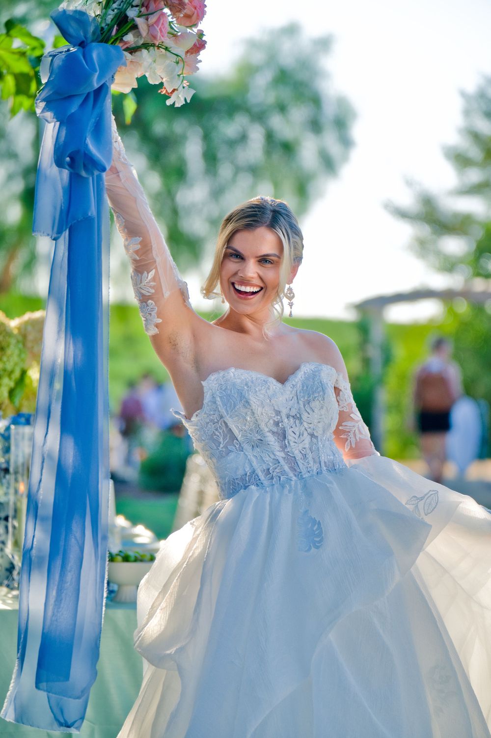 Beautiful wedding decor featuring a white floral arch with flowing blue ribbons in an outdoor garden setting.