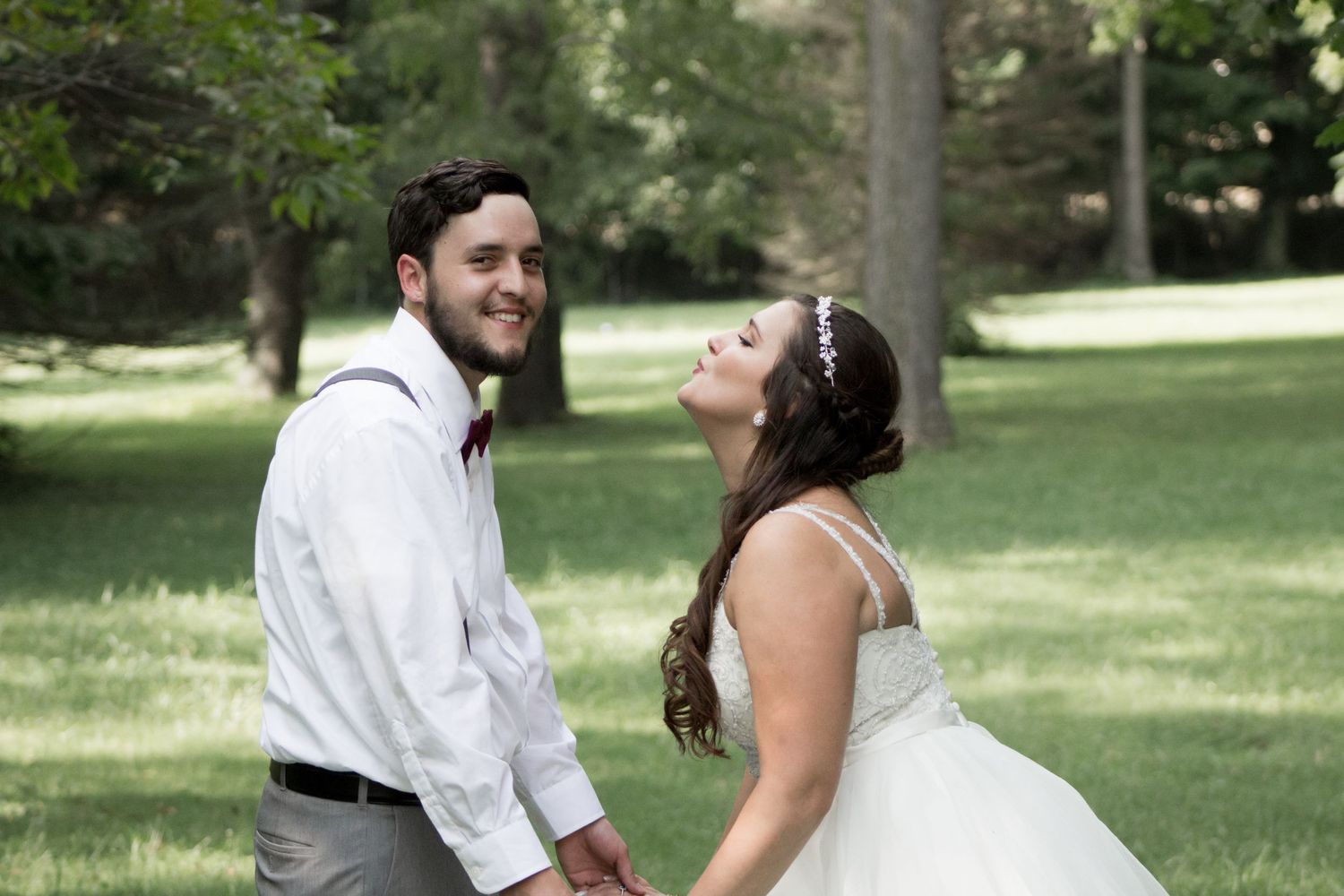 Joyful bride and groom holding hands on a lush green lawn.