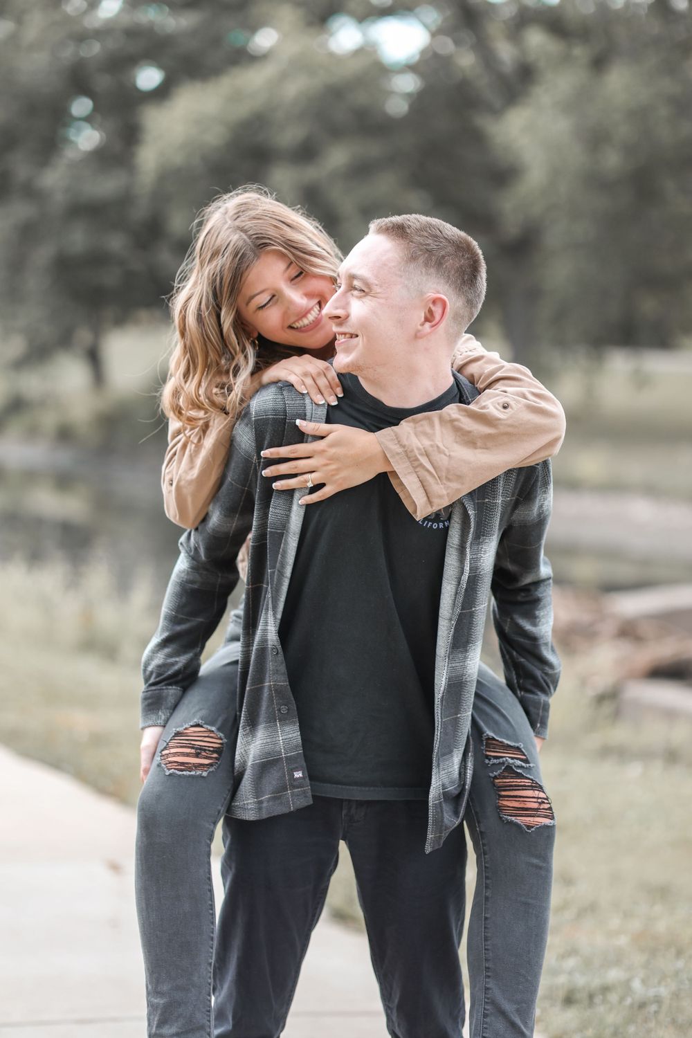 Playful couple embracing and laughing together on a nature path.