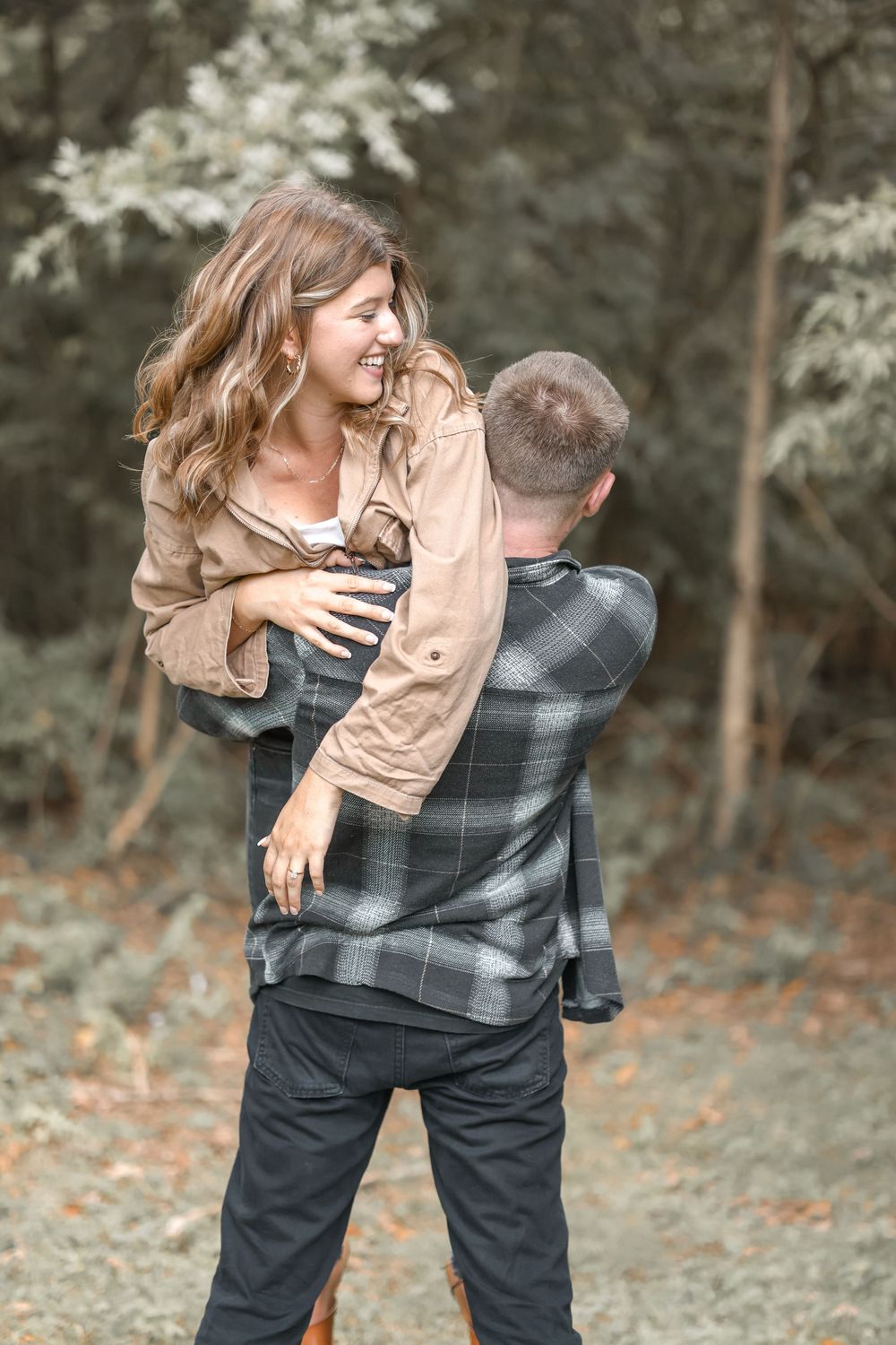 Playful couple enjoys a fun moment during their autumn photoshoot in nature.