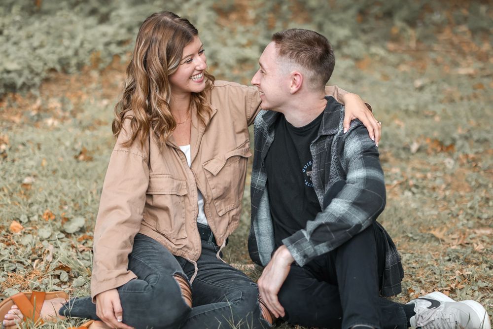 Couple sits together sharing a joyful moment during their fall photo session.