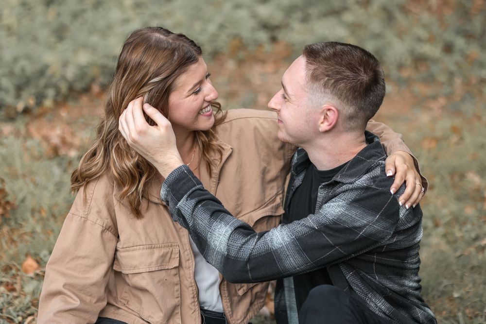 Intimate couple embracing while wearing casual jackets in an outdoor autumn setting.