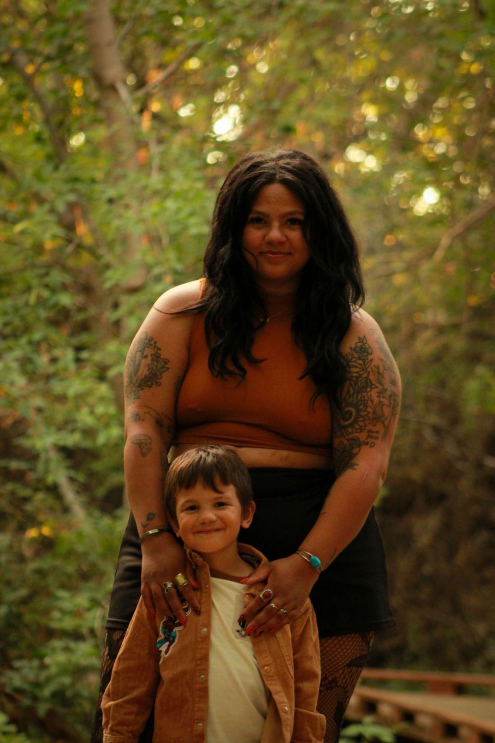 Adult and child standing together outdoors with autumn foliage in background.