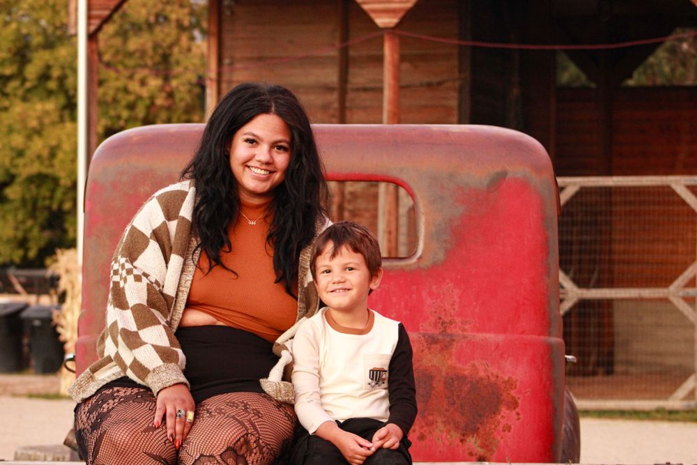 A cozy autumn portrait on a red playground structure with fall foliage in the background.