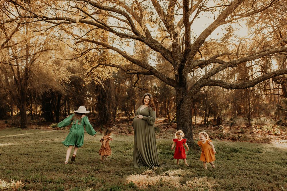 Family dances together in whimsical autumn scene with golden trees.