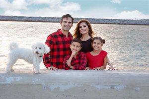Parents and children laughing together during a coastal family photo session with parents and dog