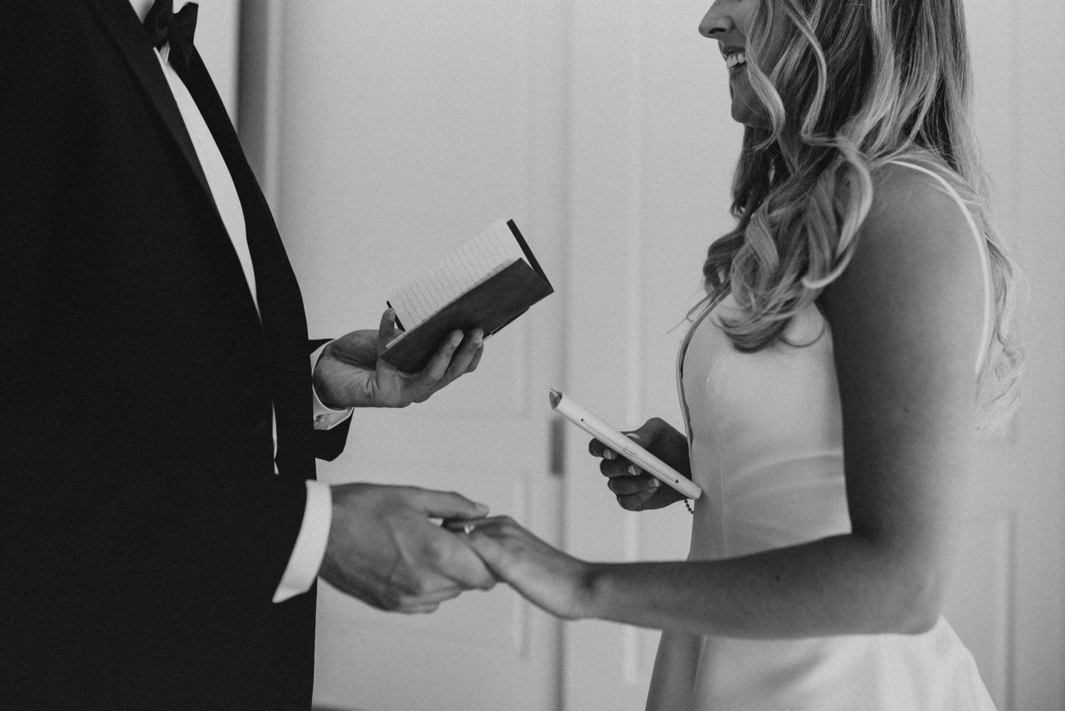 Black and white photo of couple exchanging vows and rings during an intimate wedding ceremony.