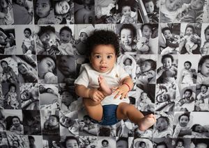 Baby wearing white onesie sits on patterned black and white photo collage backdrop.