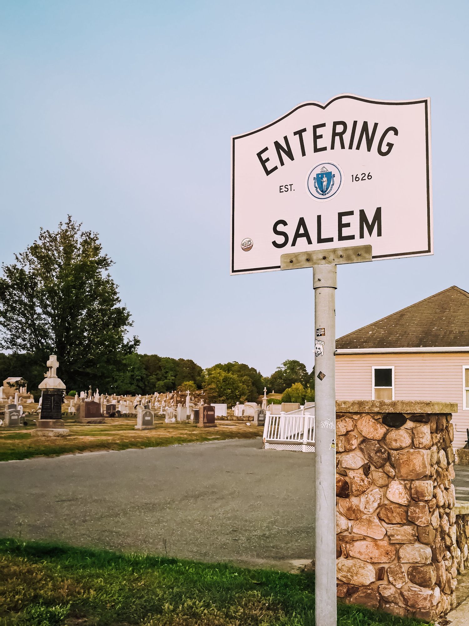 A sequence of stone pillars with signs reading 'SALEM' and 'ENTERING' along a grassy roadside path.