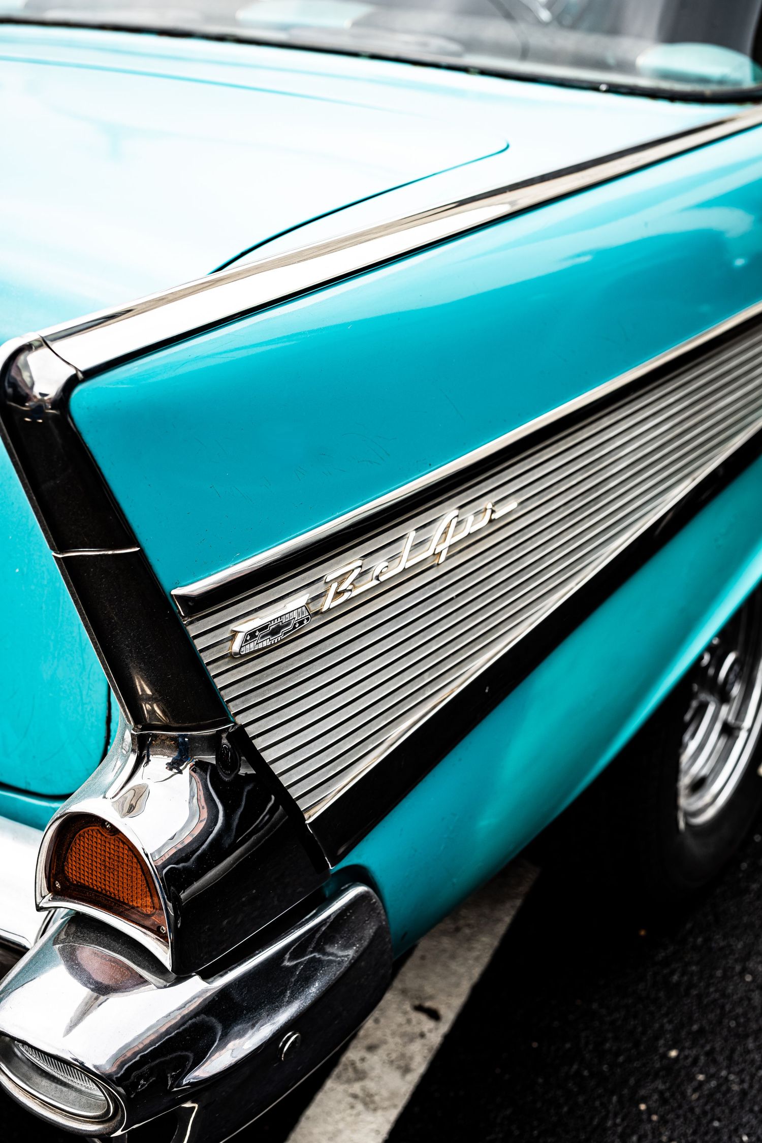 Close-up detail of a turquoise 1957 Chevrolet Bel Air showing chrome trim and distinctive tailfin design.