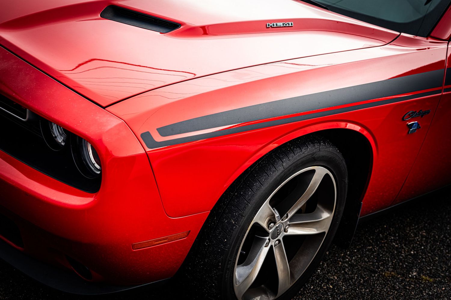 Close-up details of a red classic muscle car showcasing its sleek body panels and chrome accents.