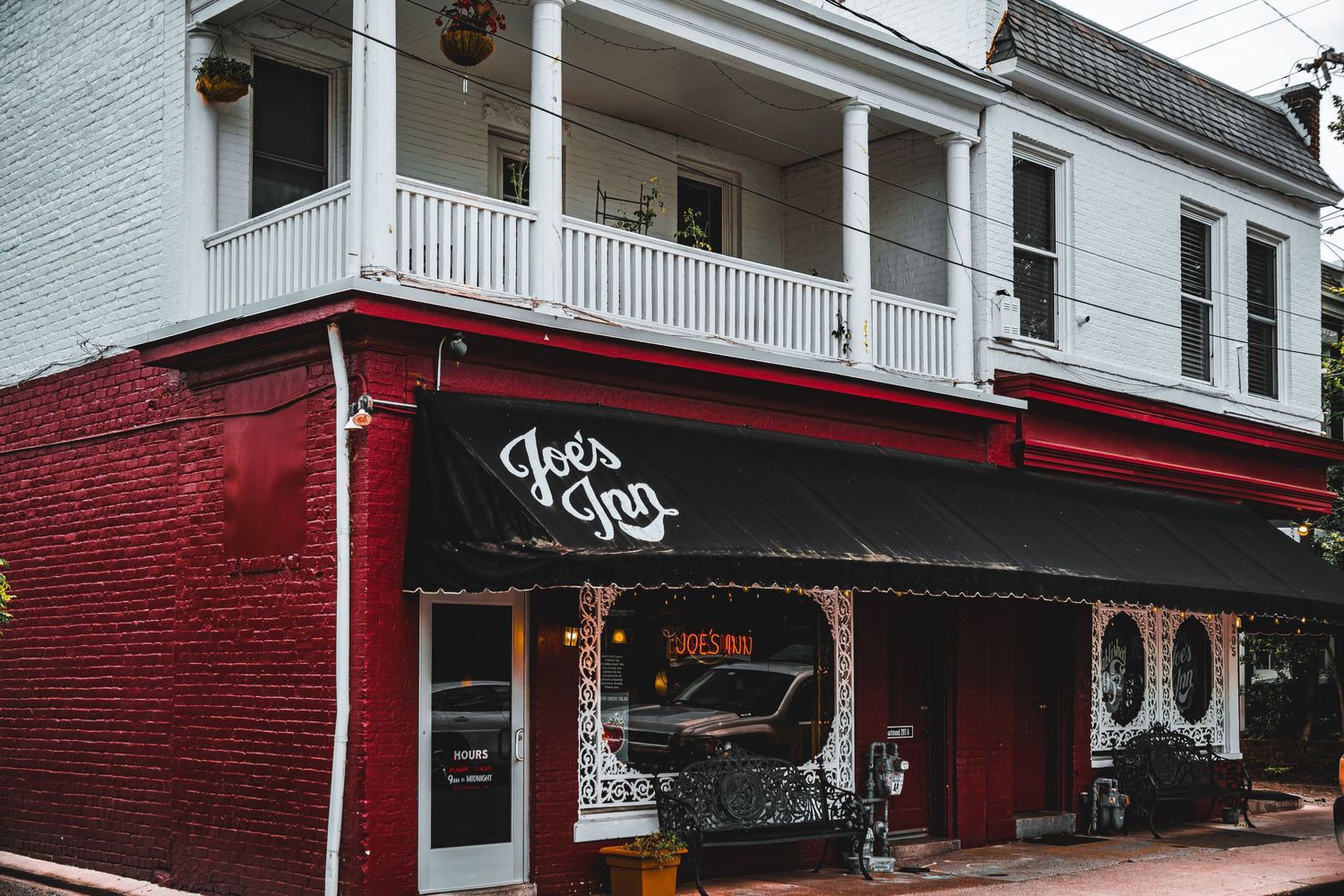 Historic red brick building with white columned porch and graffiti art on the storefront in an urban setting.