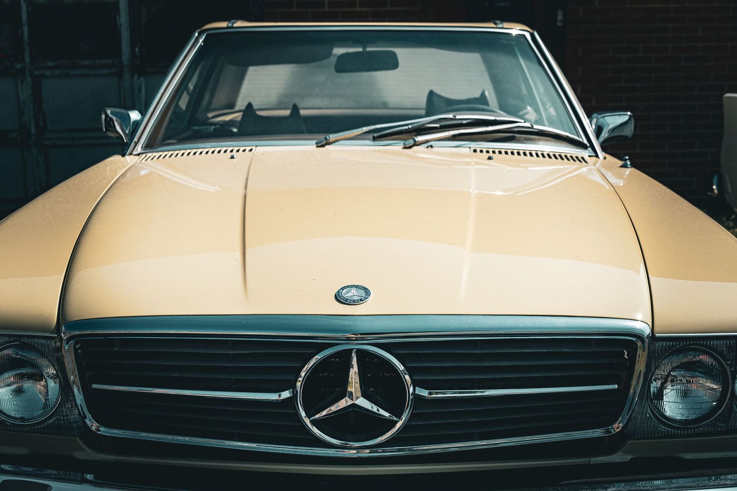 A row of vintage luxury car grilles and front ends showcasing classic Mercedes-Benz and other automotive designs.