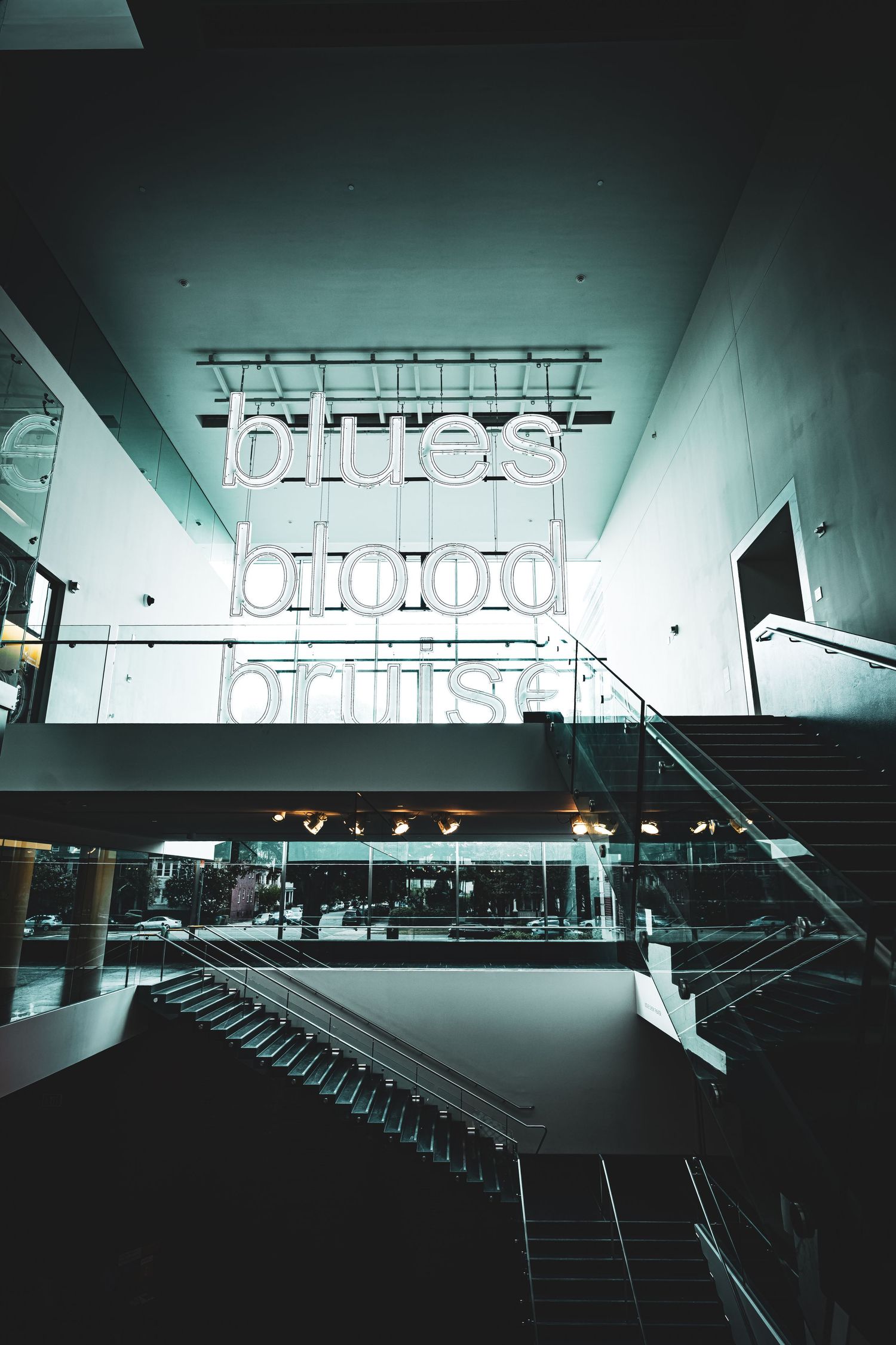 Dark moody architectural interior with illuminated signage and staircase creates dramatic industrial atmosphere.