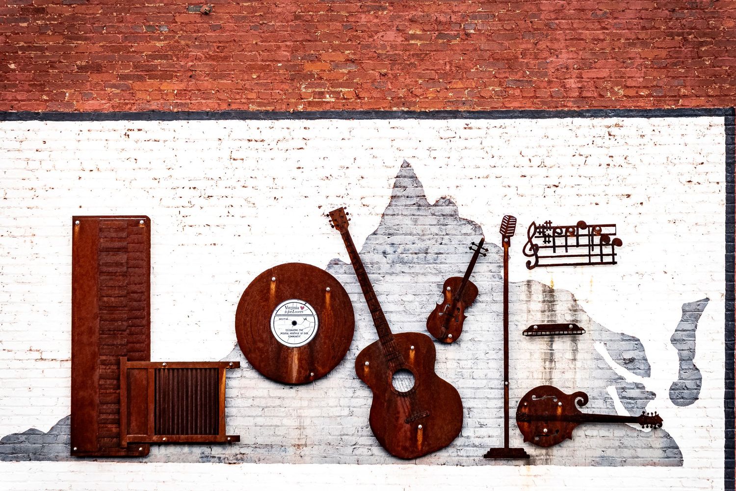 Musical instruments and decor elements cast shadows against a rustic red brick wall in an artistic arrangement.