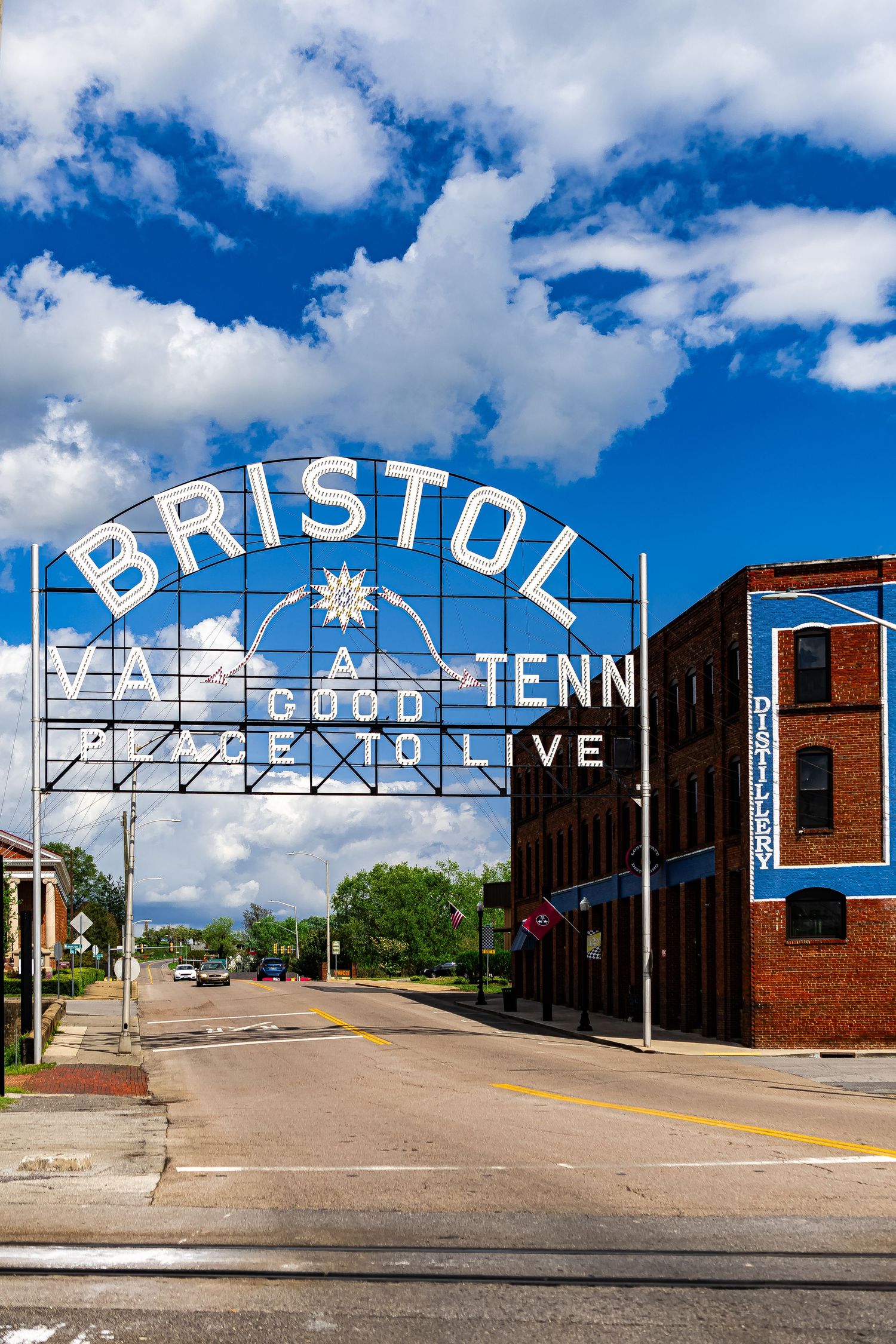 Historic Bristol Tennessee sign spans across a street with white lettering against a blue sky with puffy white clouds.