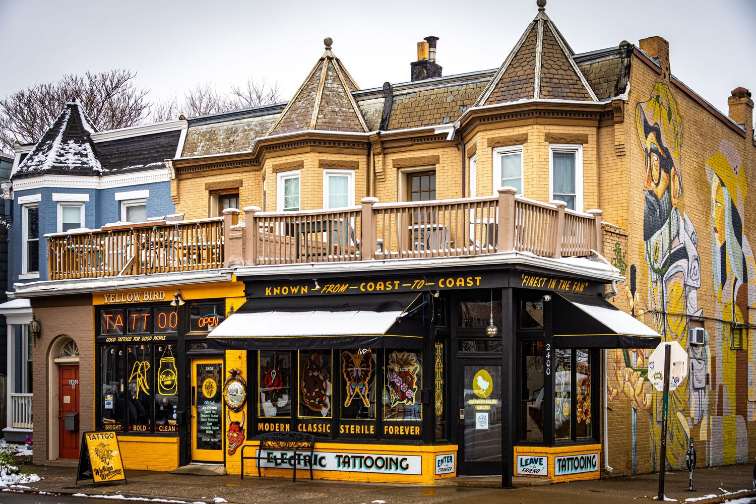 Historic storefronts and buildings line a small town street with vintage architecture and yellow accents.