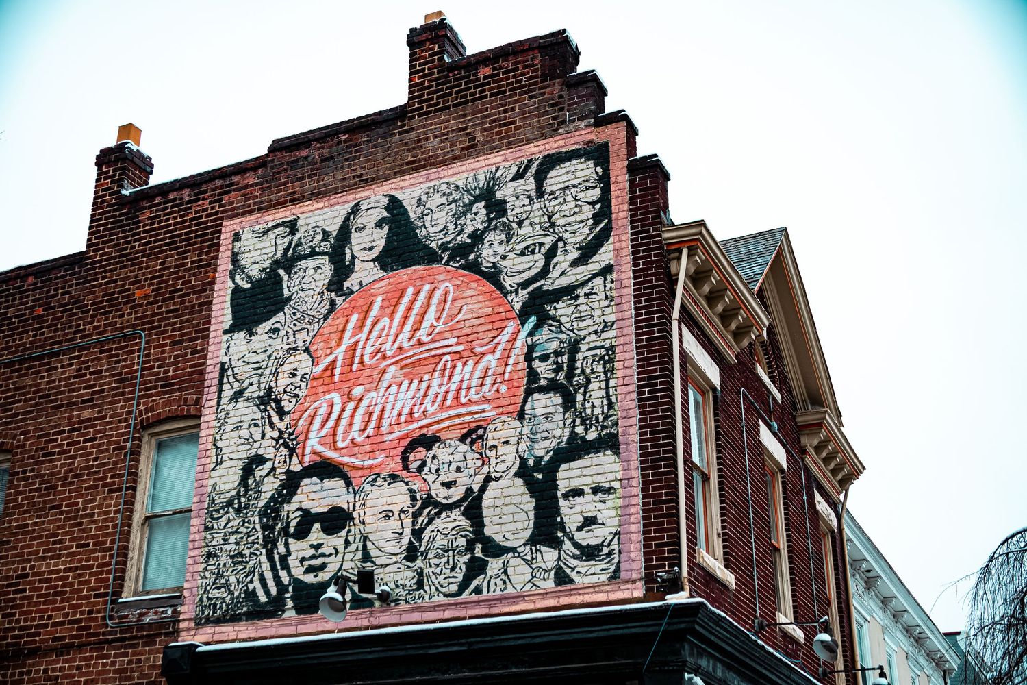 Vintage-style mural artwork on brick building exterior shows retro advertising and decorative elements in urban setting.