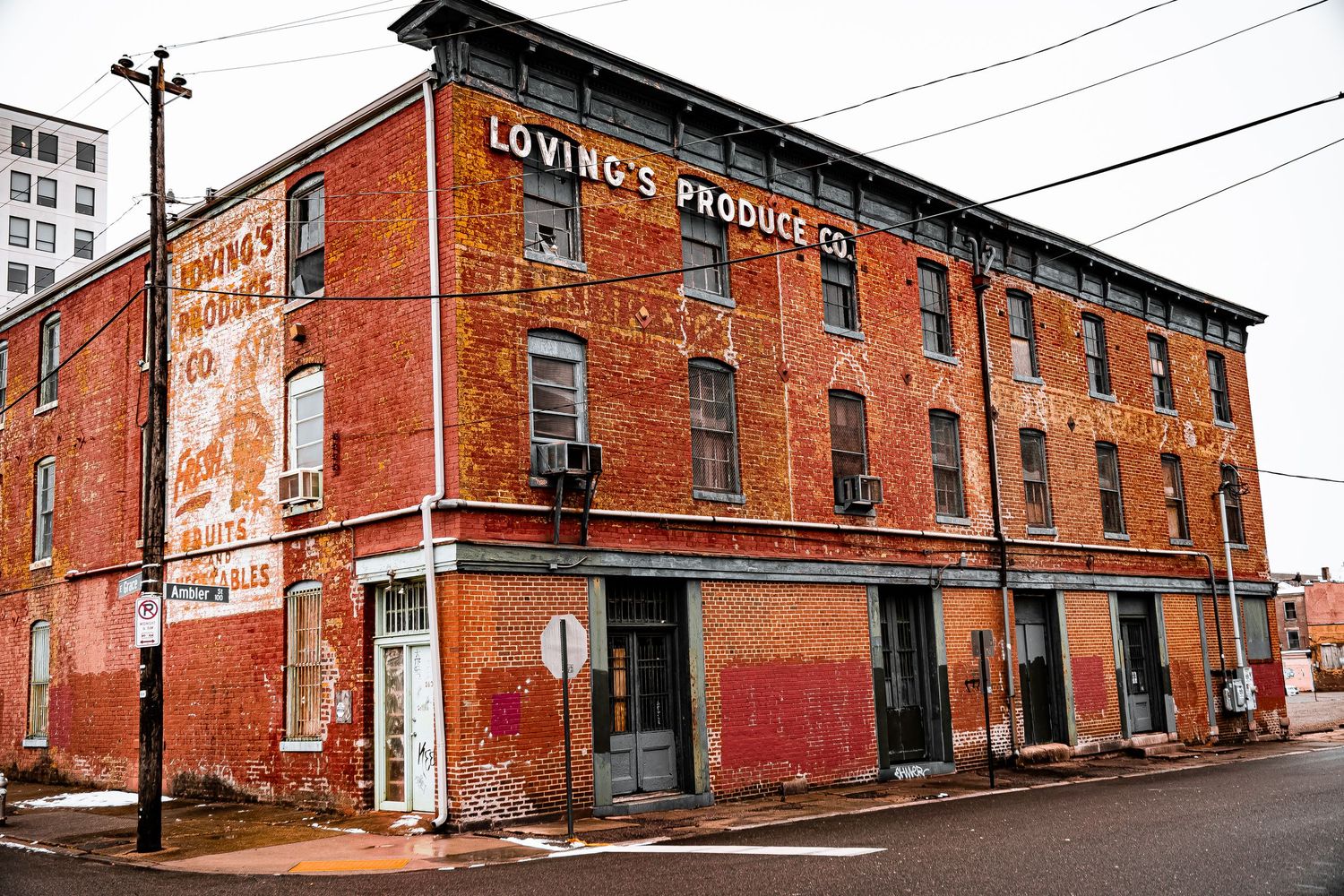 Old red brick industrial buildings with faded signs line a street in a historic manufacturing district.