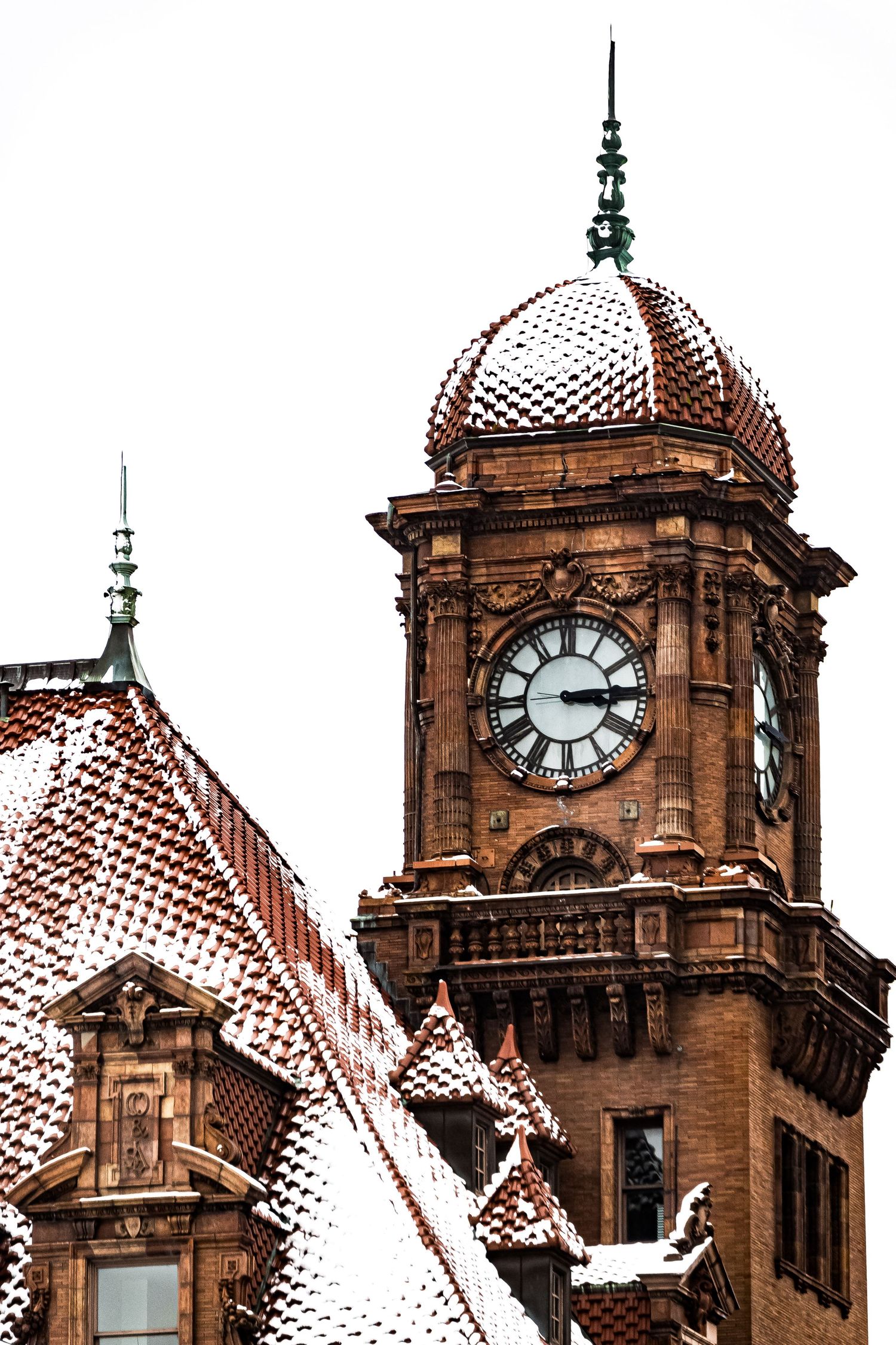 Snow-dusted clock tower and domed roof of a Victorian-era building captured in close-up detail.