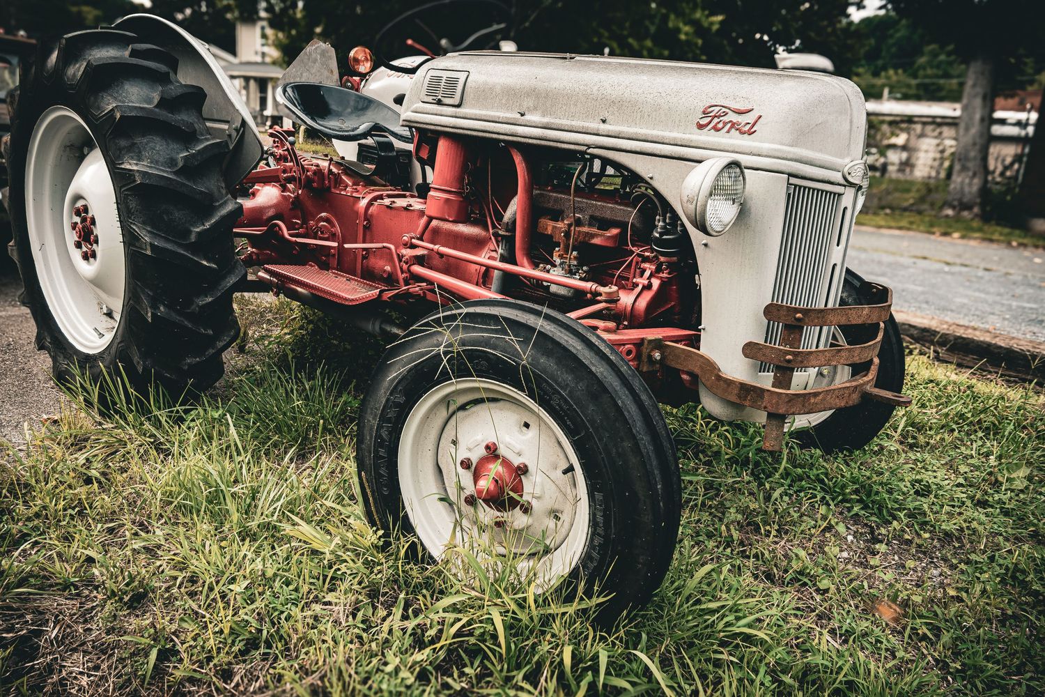 Close-up view of vintage tractor wheels and mechanical parts in a grassy field.