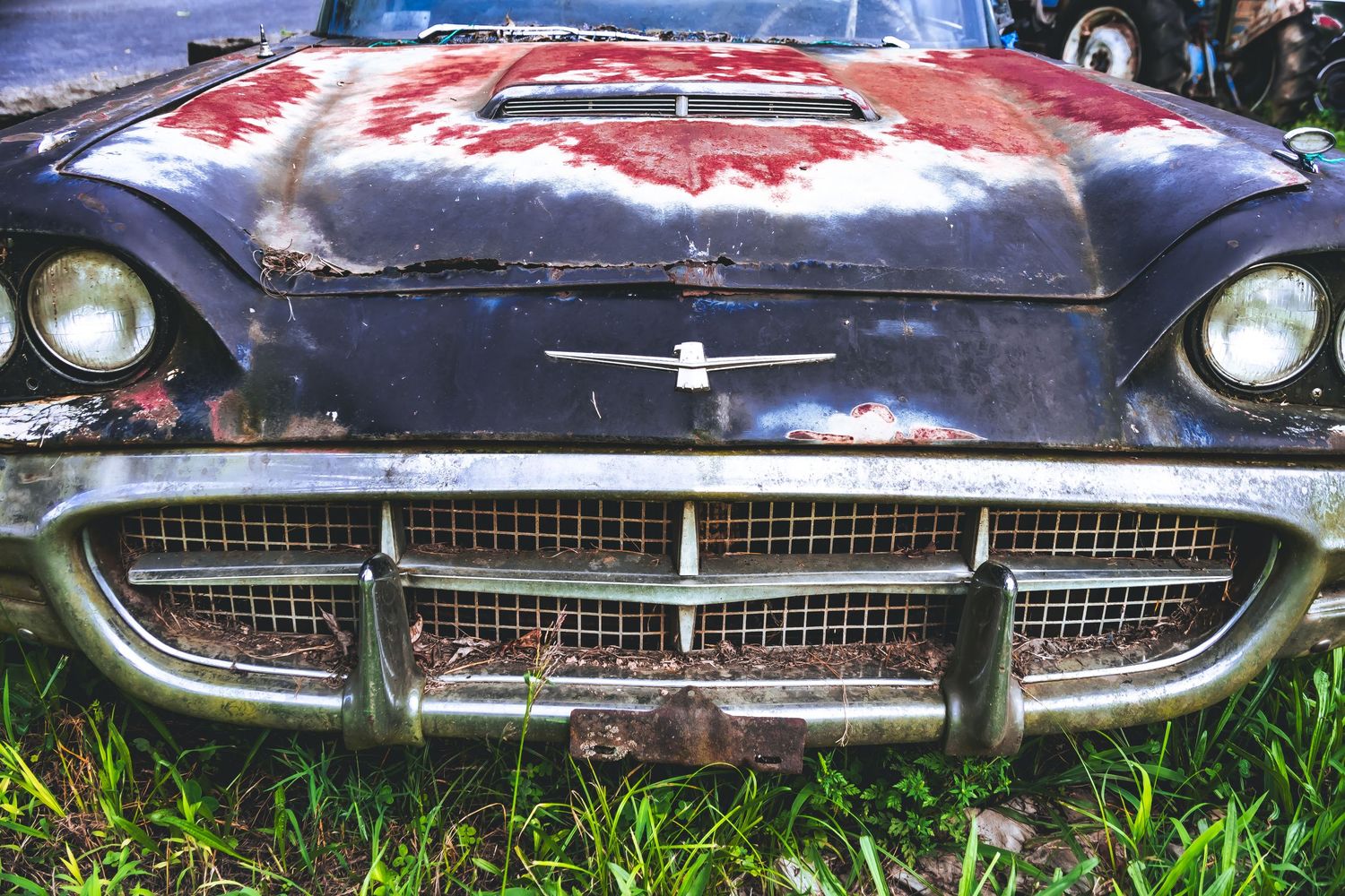 Close-up view of rusted vintage Chevrolet car grilles showing weathered chrome details and deteriorating paint finishes.