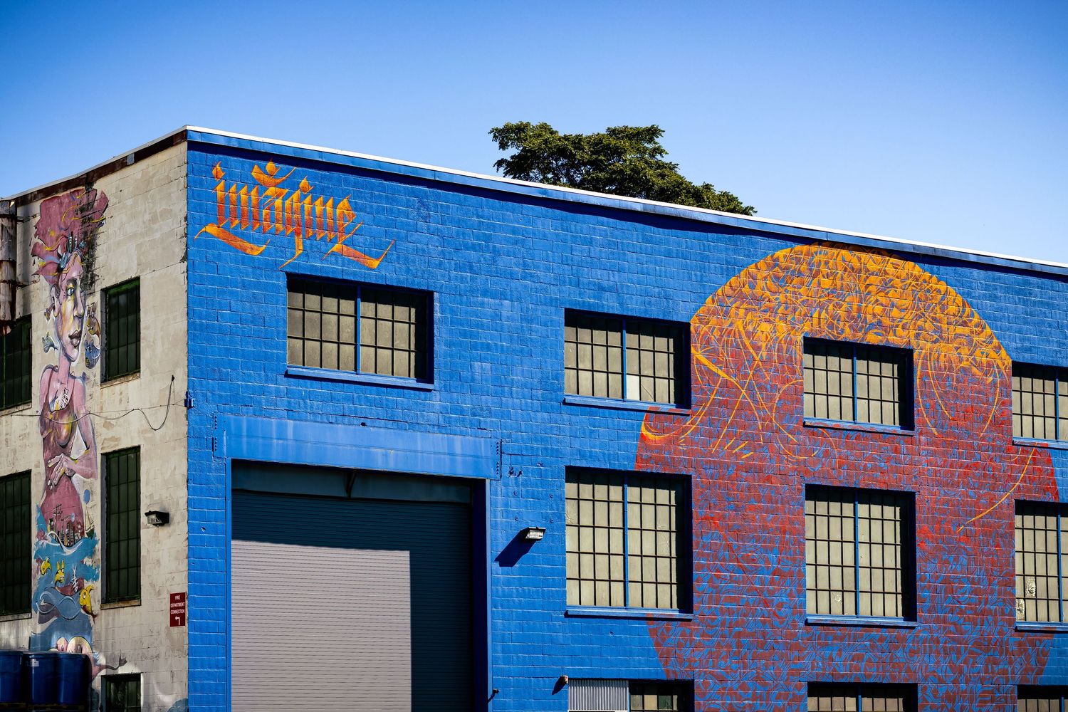 A bright blue industrial building exterior with decorative orange and red graffiti art along its walls.