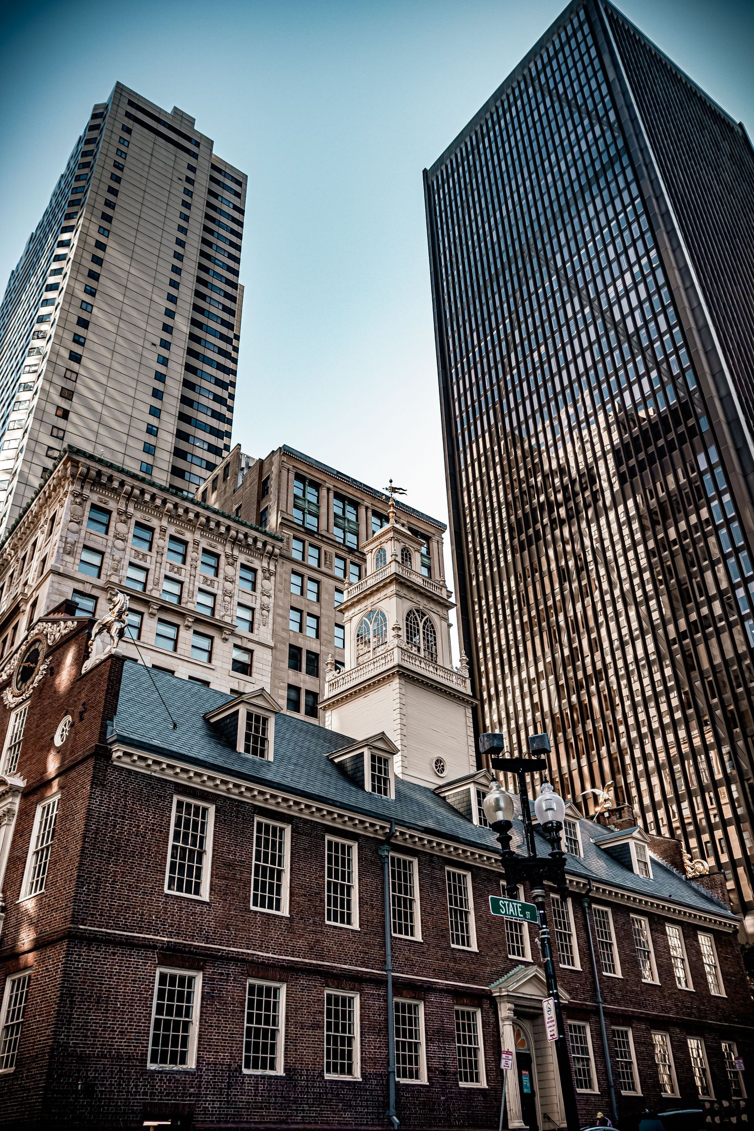 Historic Old State House building in Boston contrasts with modern skyscrapers towering above in the downtown skyline.
