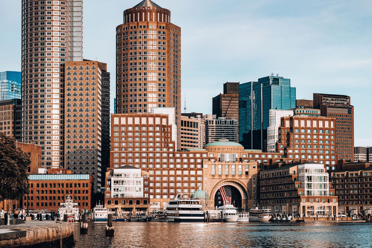 Panoramic view of Boston's waterfront skyline with historic buildings and modern skyscrapers along the harbor.
