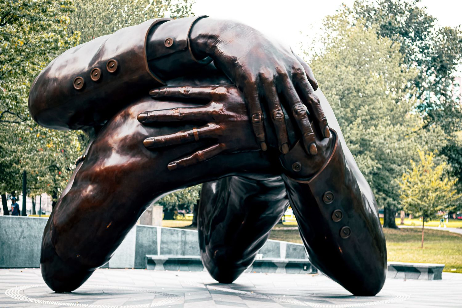 A series of close-up photos showing a dark bronze sculpture of a reclining figure in an outdoor park setting.