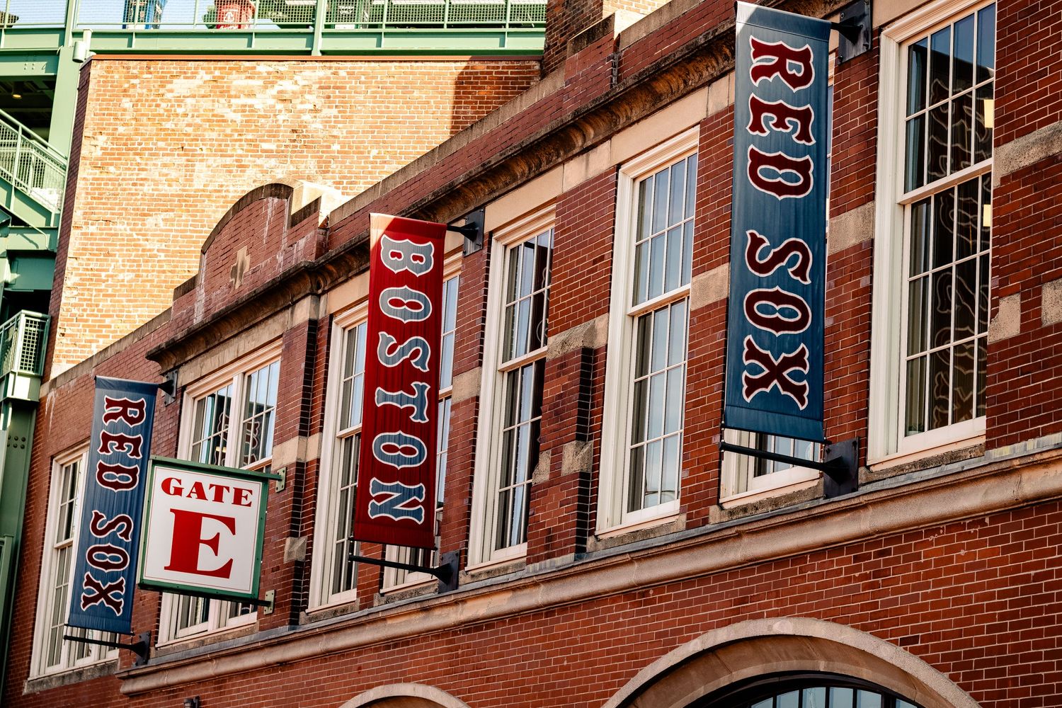 Colorful championship banners and flags hang from the brick exterior of Fenway Park baseball stadium in Boston.