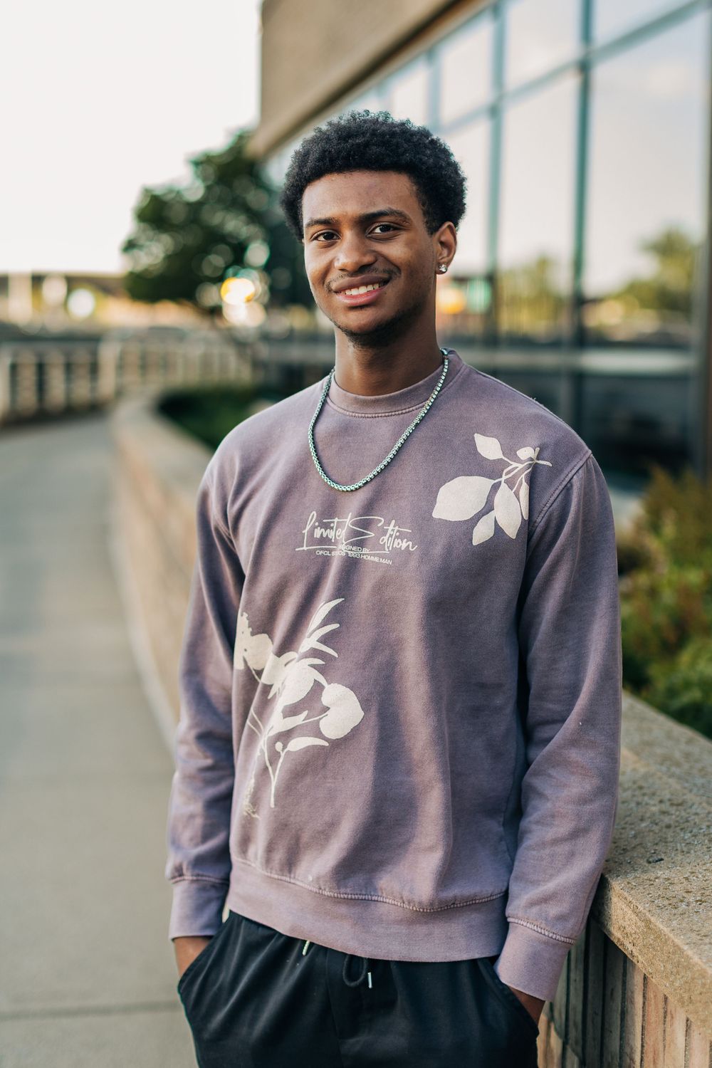 Four photos in sequence show someone wearing a purple sweatshirt with white graphic design sitting outdoors.