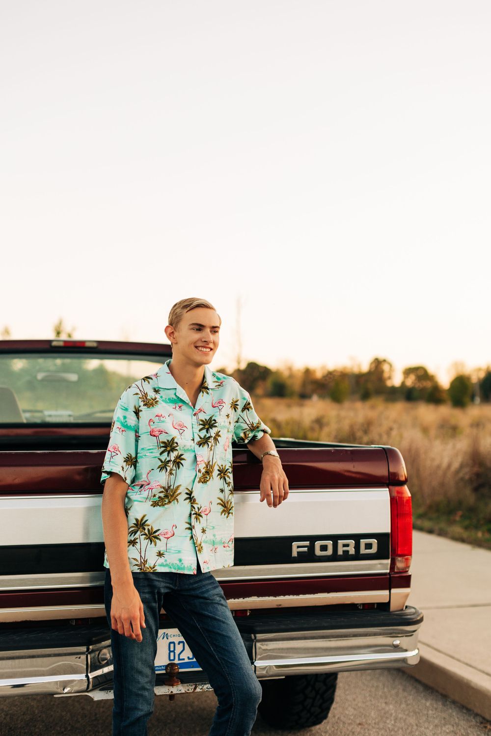 Casual pose on the tailgate of a Ford pickup truck in a tropical print shirt at sunset.