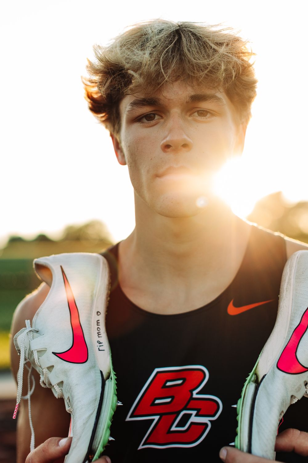 Athletic person holding Nike running shoes during golden hour photography session.
