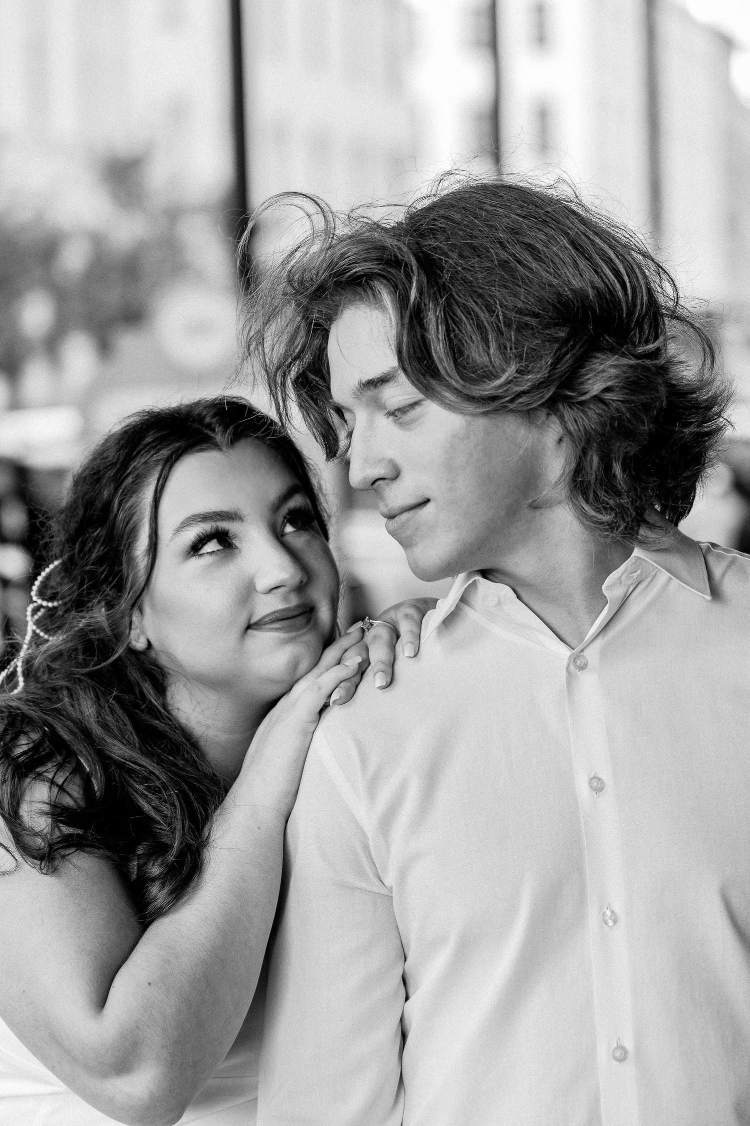 A couple shares an intimate black and white moment together on a city street.